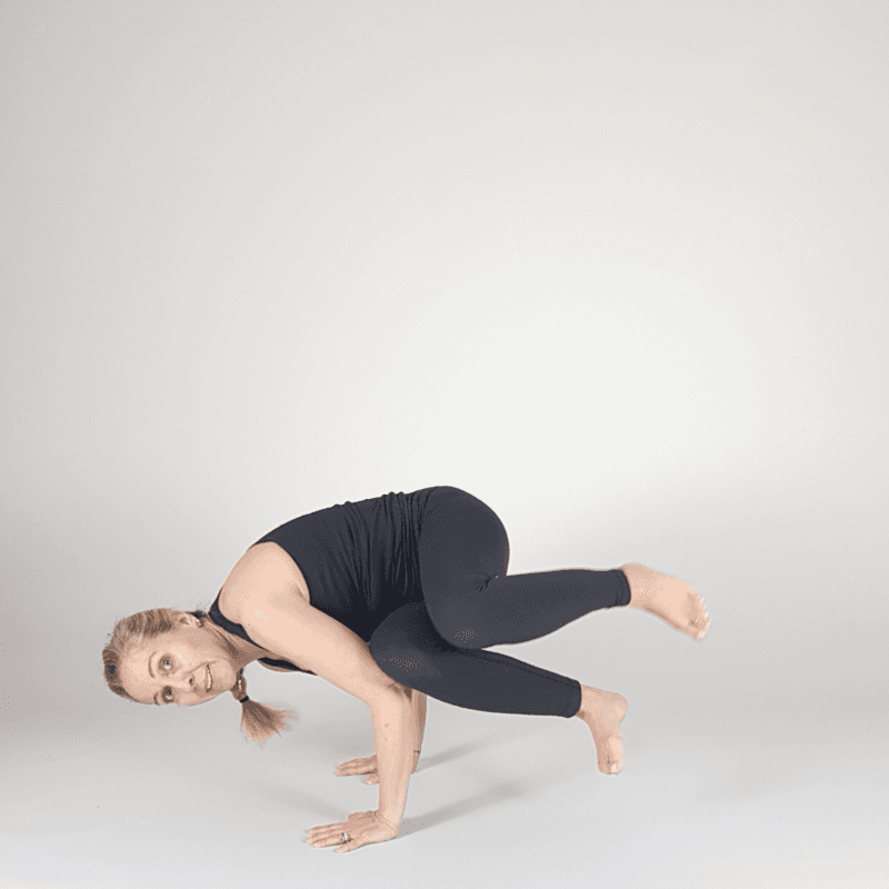 Yoga practitioner in Extended Leg Crow with one leg reaching back.