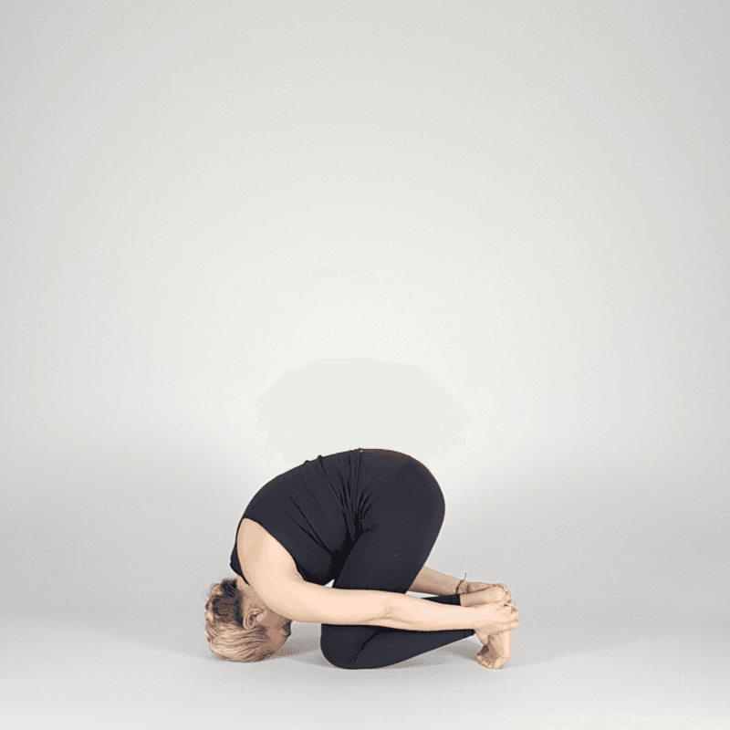 Yoga practitioner holding ankles in Ear Pressure Hold pose