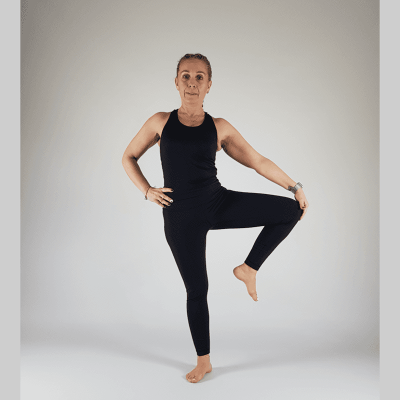 Yoga practitioner in Tree Pose with both hands resting on the lifted knee