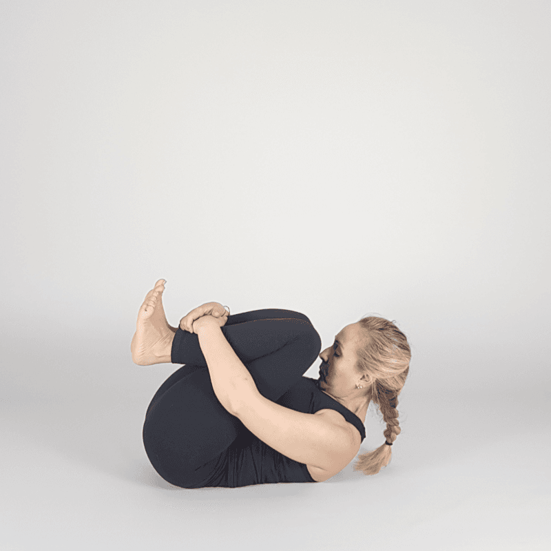 Yoga practitioner hugging knees to chest.