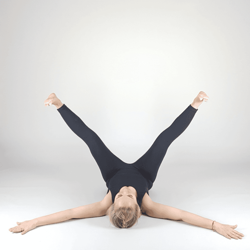 Yoga practitioner in supine wide leg stretch.