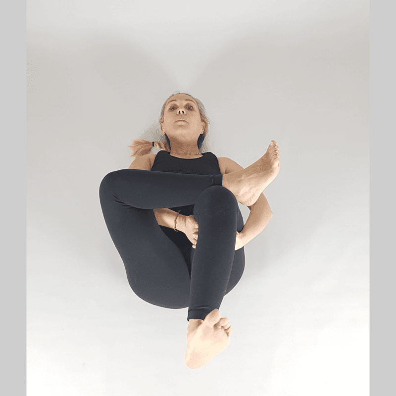 Yoga practitioner in Supine Spinal Twist with knees dropped to side.