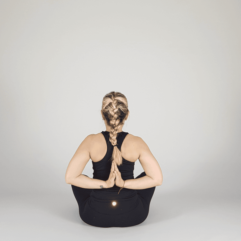 Yoga practitioner performing Bound Lotus with reverse prayer hands.