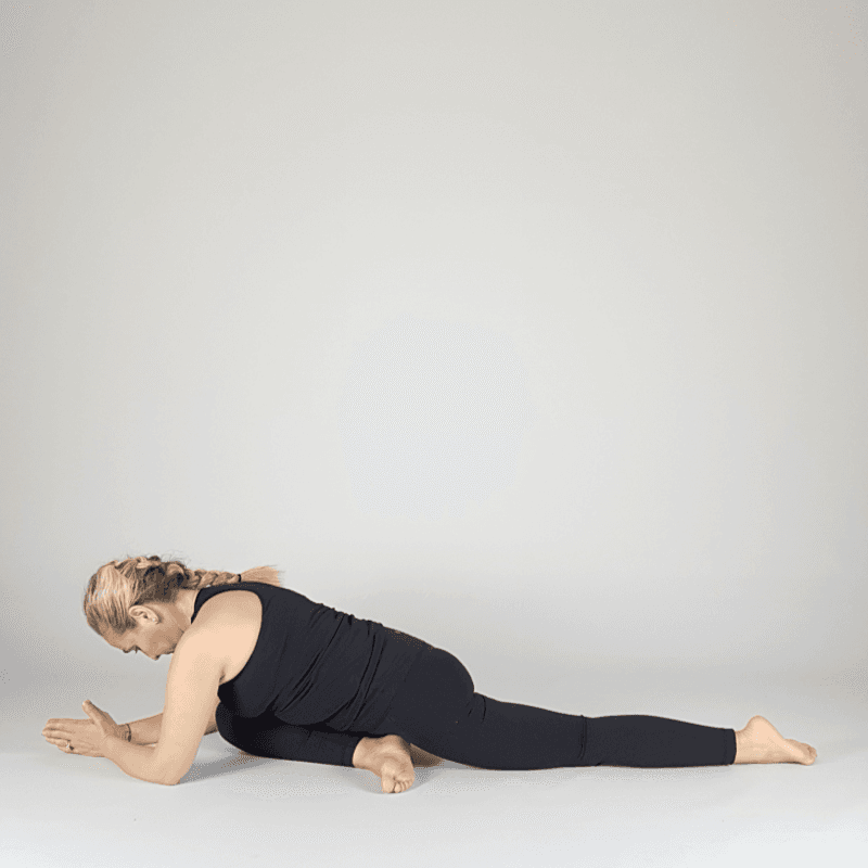 Yoga practitioner resting on forearms in pigeon pose.