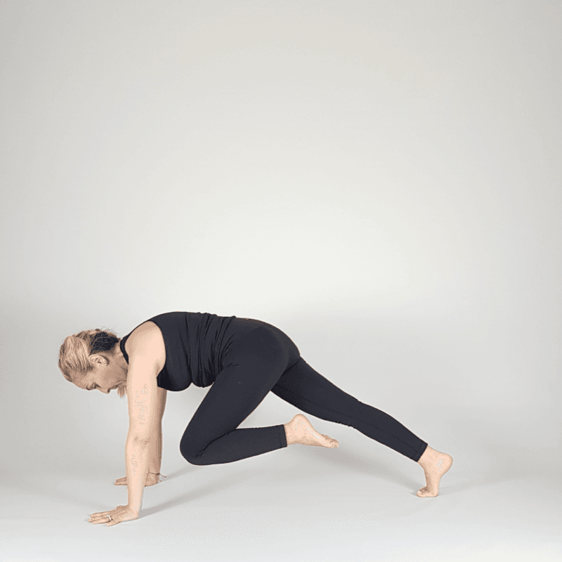 Yoga practitioner drawing knee to chest in Plank position