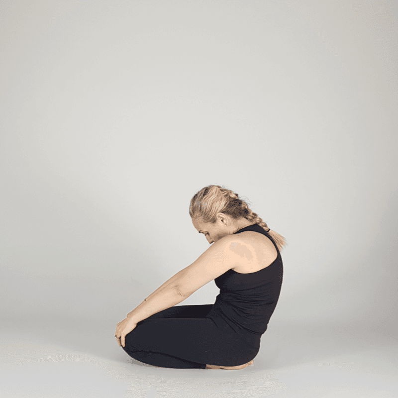Yoga practitioner seated in neutral kneeling pose.