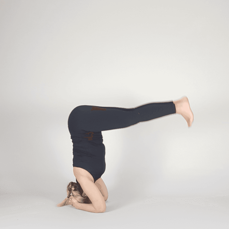 Yoga practitioner hovering legs just off floor in headstand.