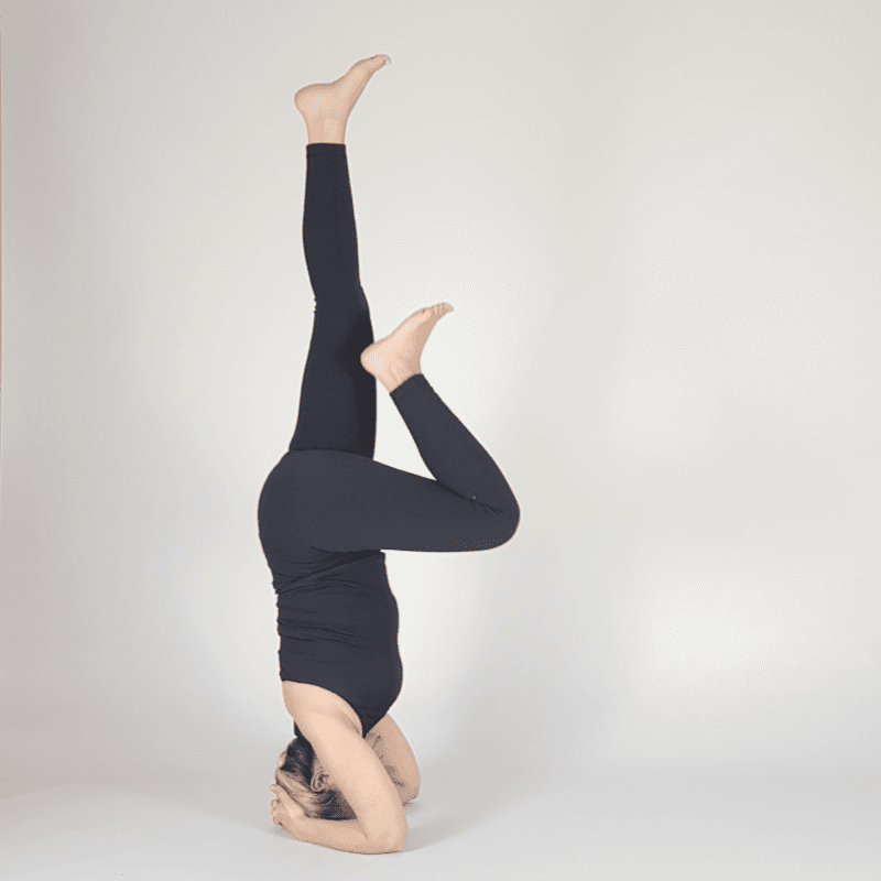 Yoga practitioner lifting one leg in Headstand.