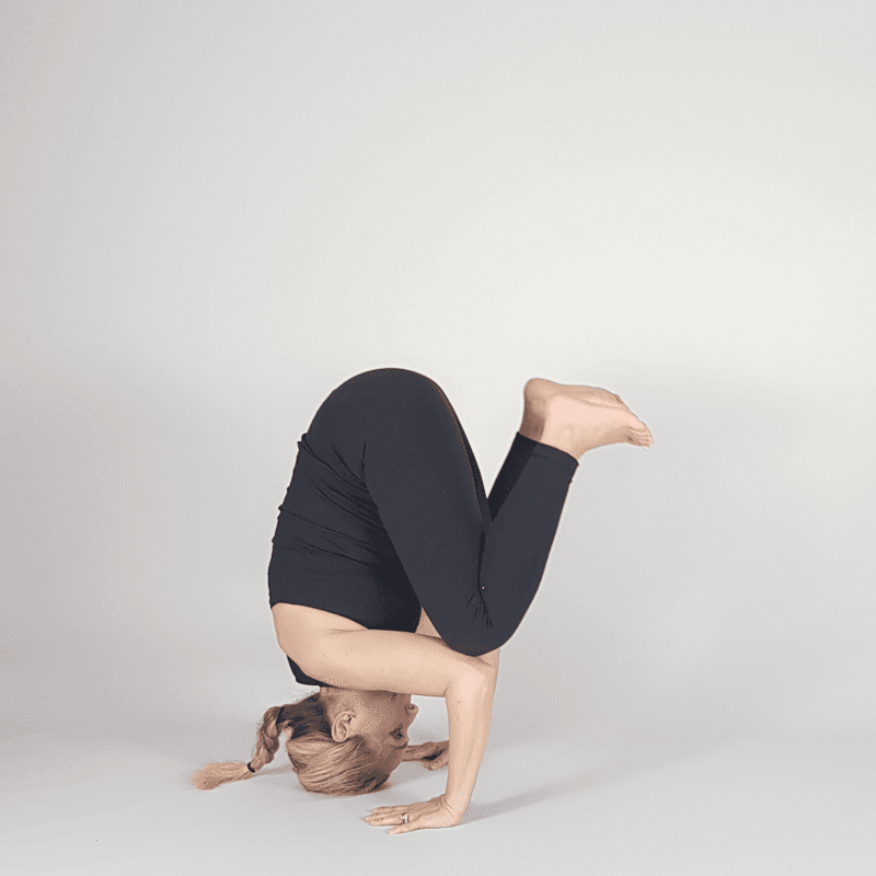 Yoga practitioner holding tucked tripod headstand position.