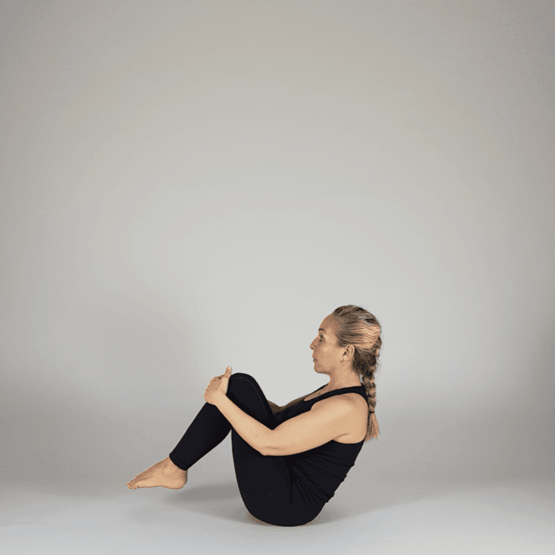 Yoga practitioner holding a bent-knee boat pose.