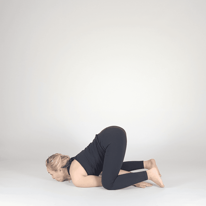 Yoga practitioner resting in compact Child's Pose.