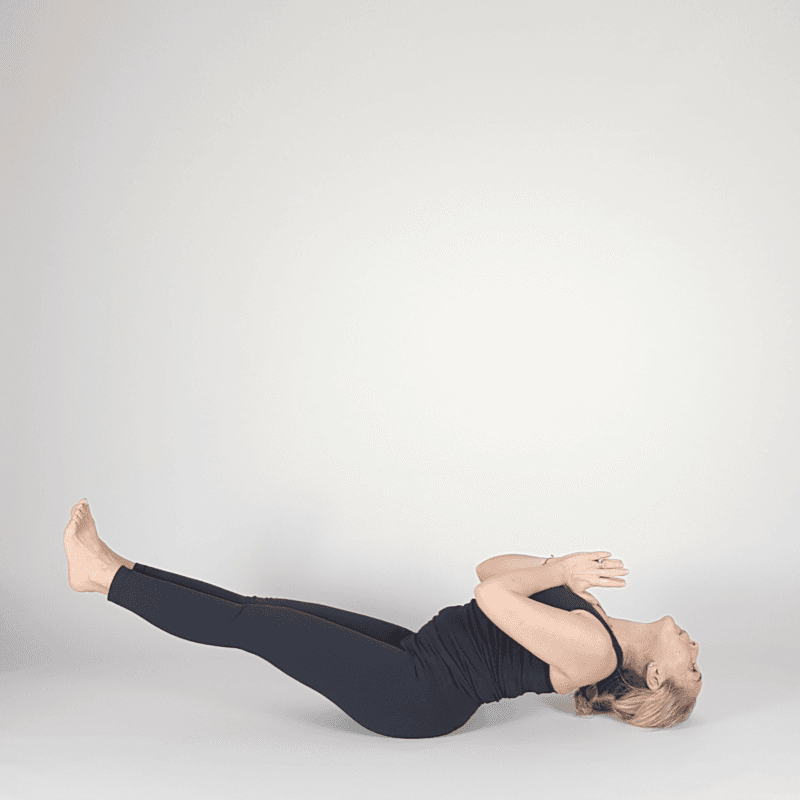 Yoga practitioner lifting both legs while lying on back.