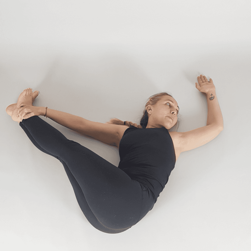 Yoga practitioner in reclined figure four hip stretch.