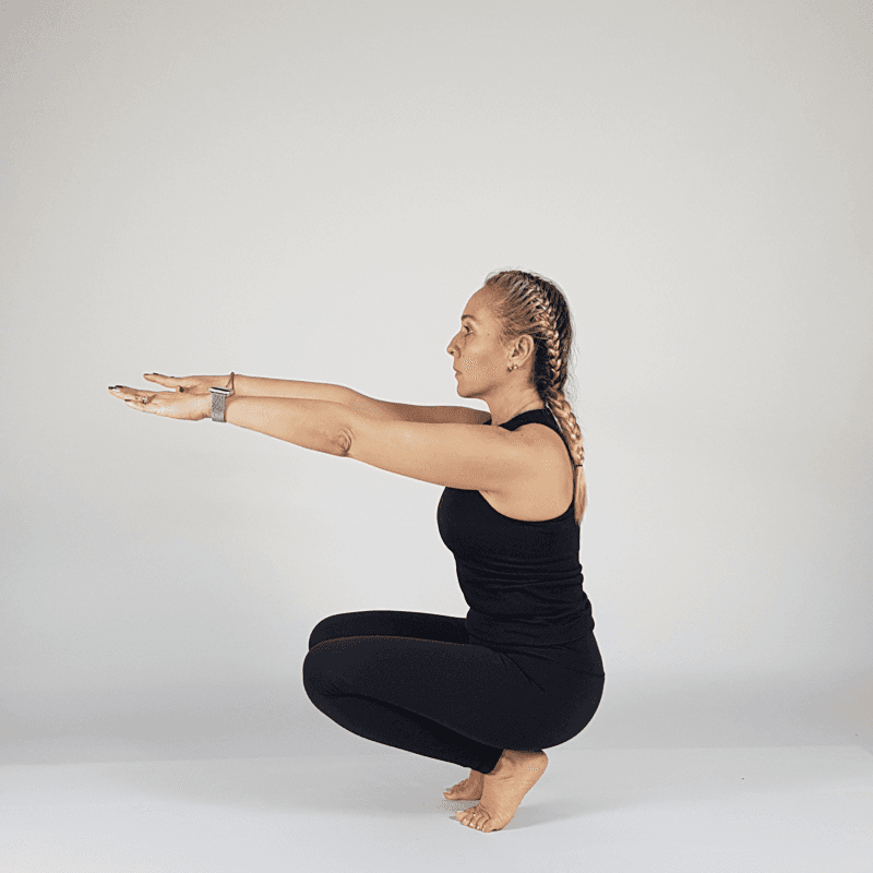 Yoga practitioner performing Garland Pose with arms extended.