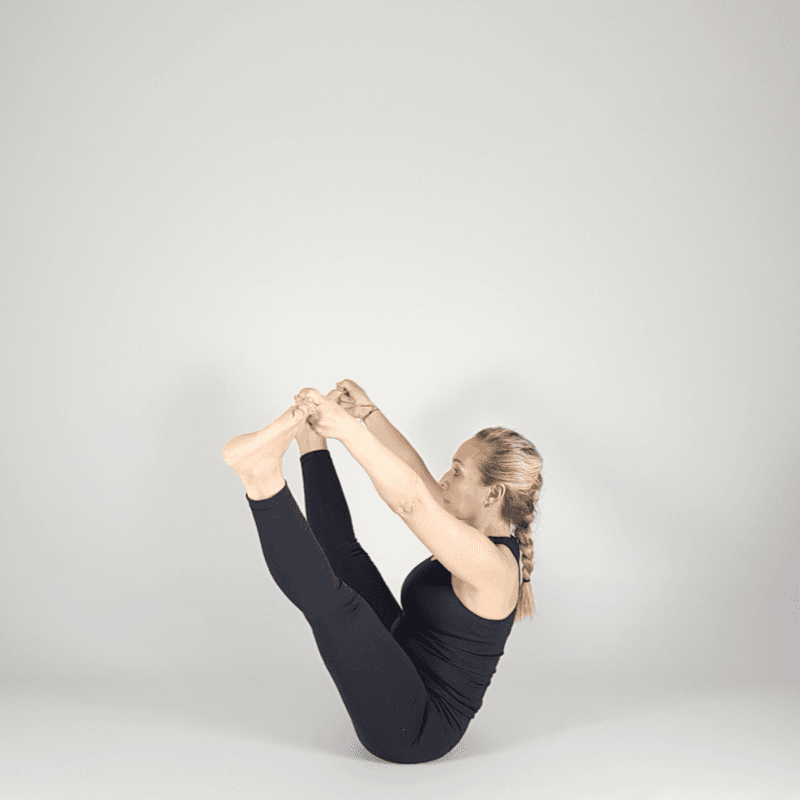 Yoga practitioner in Boat Pose with prayer hands.