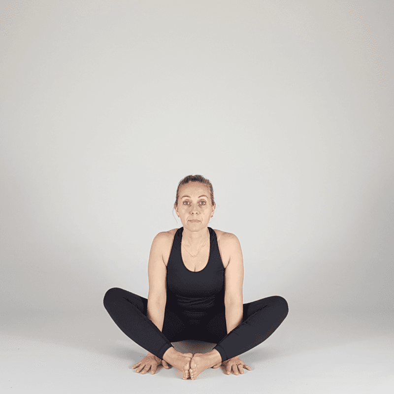 Yoga practitioner seated with hands in prayer.