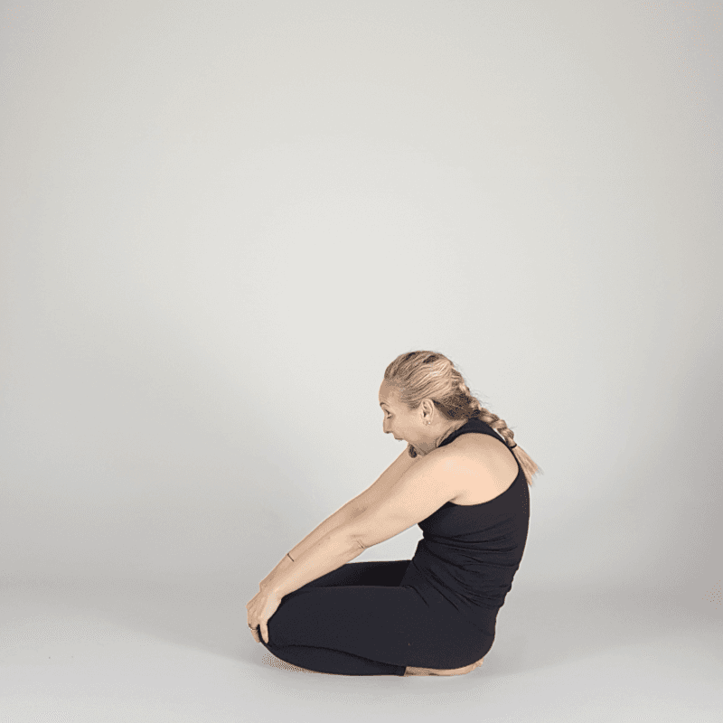 Yoga practitioner performing kneeling spinal rounding.