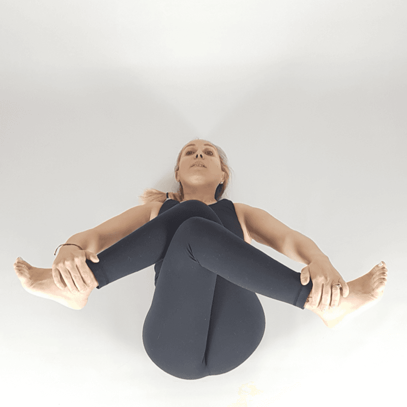 Yoga practitioner holding feet in Happy Baby Pose.
