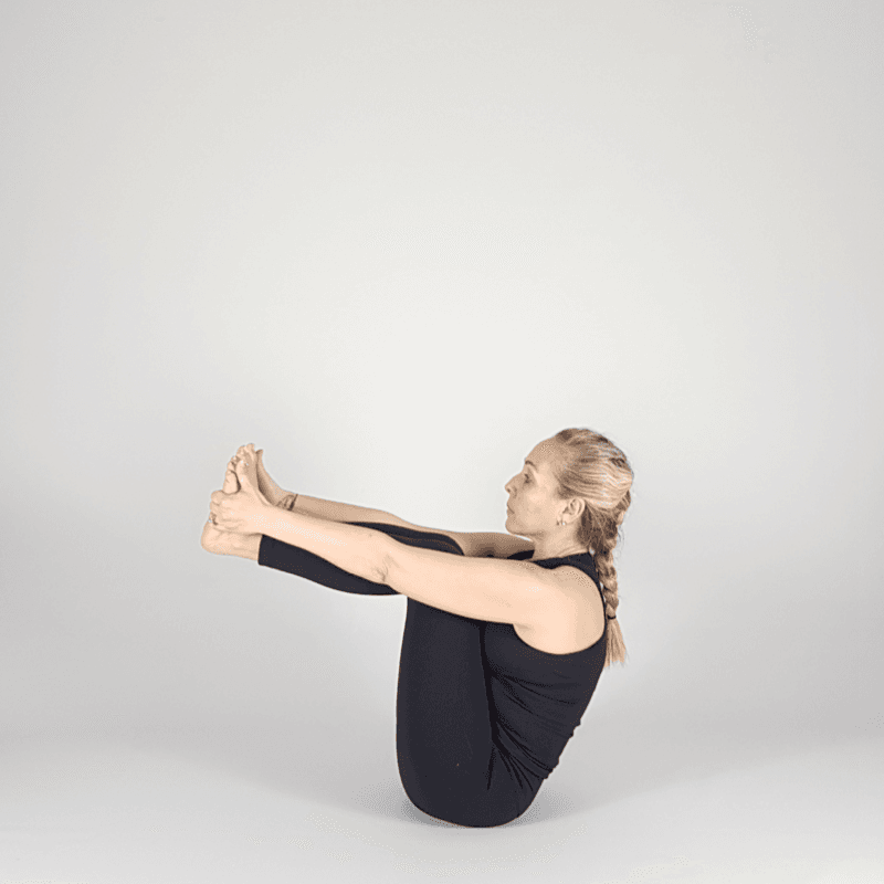 Yoga practitioner holding toes in seated pose.