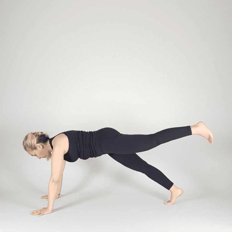 Yoga practitioner in Three-Legged Plank with one leg lifted