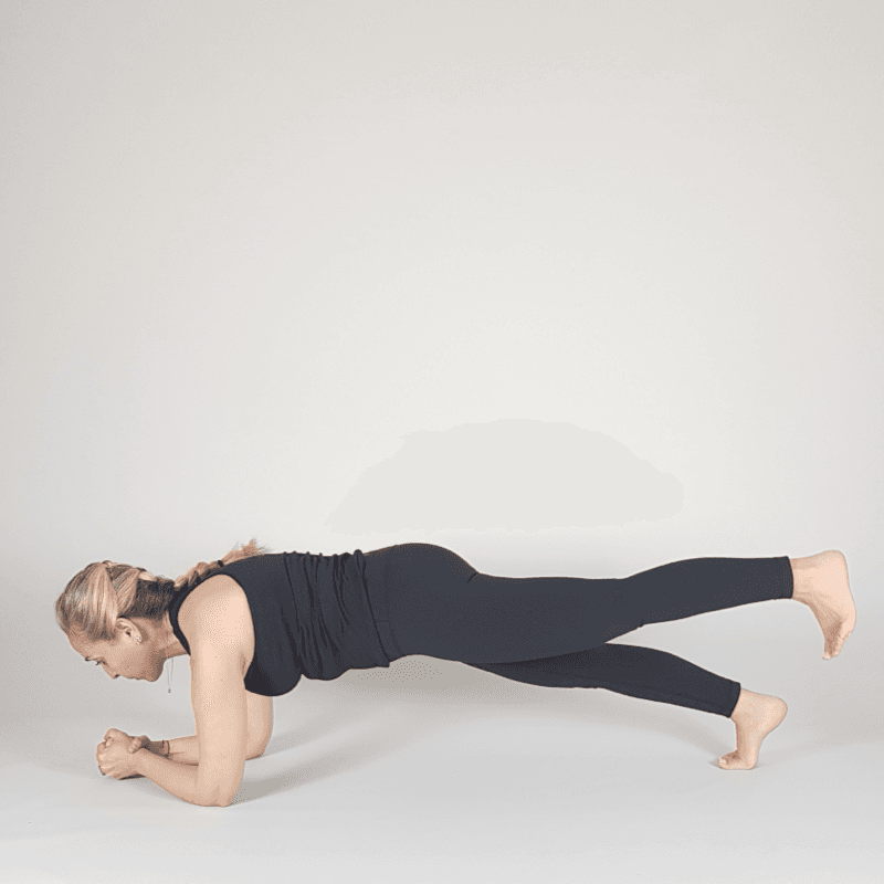 Yoga practitioner lifting leg in Forearm Plank position