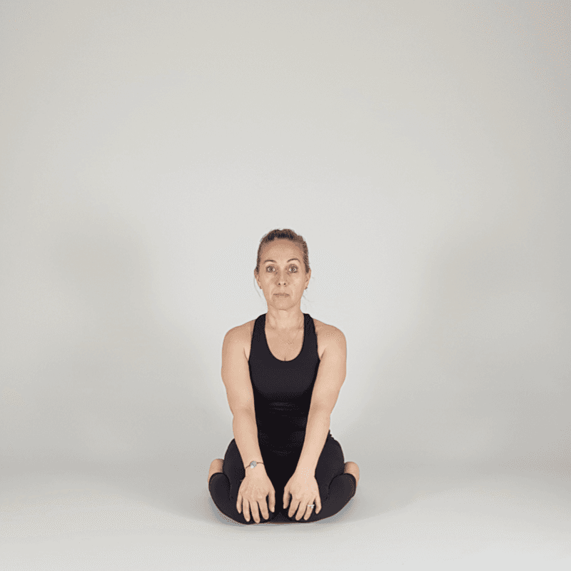 Yoga practitioner sitting in neutral seated pose.