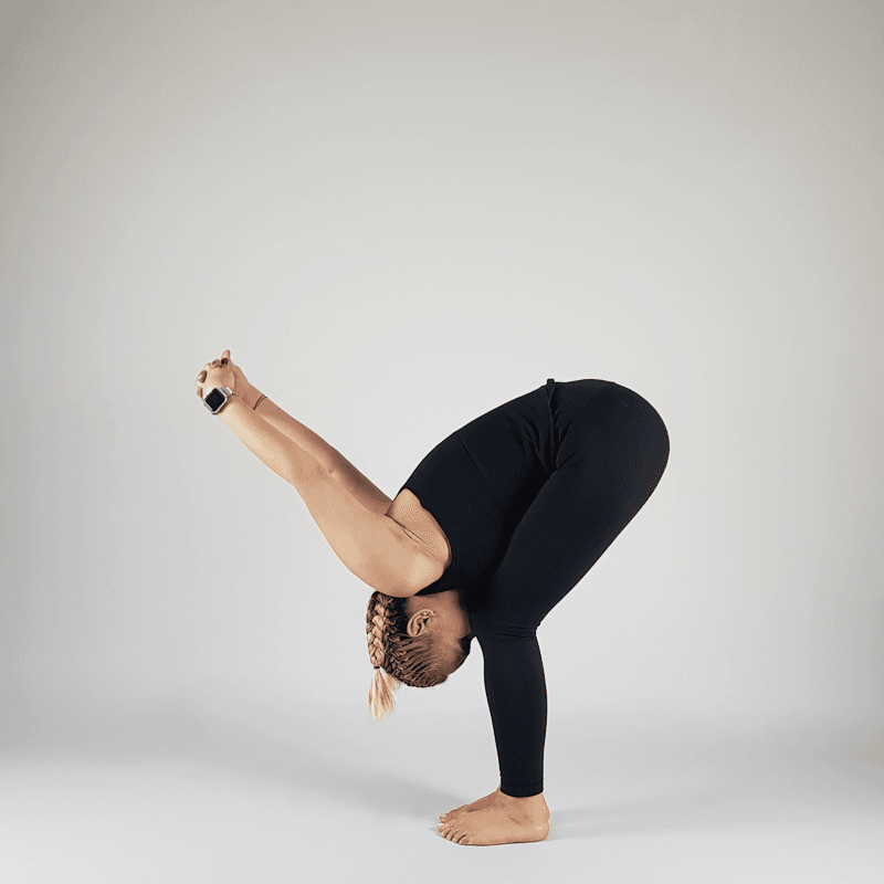 Yoga practitioner in forward fold with hands in reverse prayer behind back