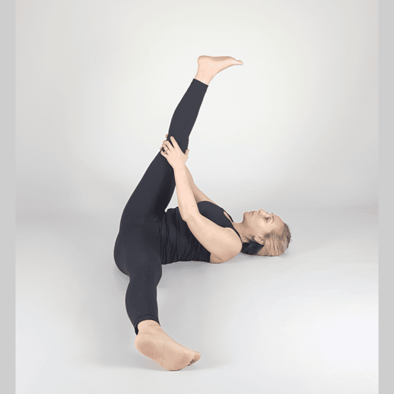 Yoga practitioner stretching hamstring while lying on back.