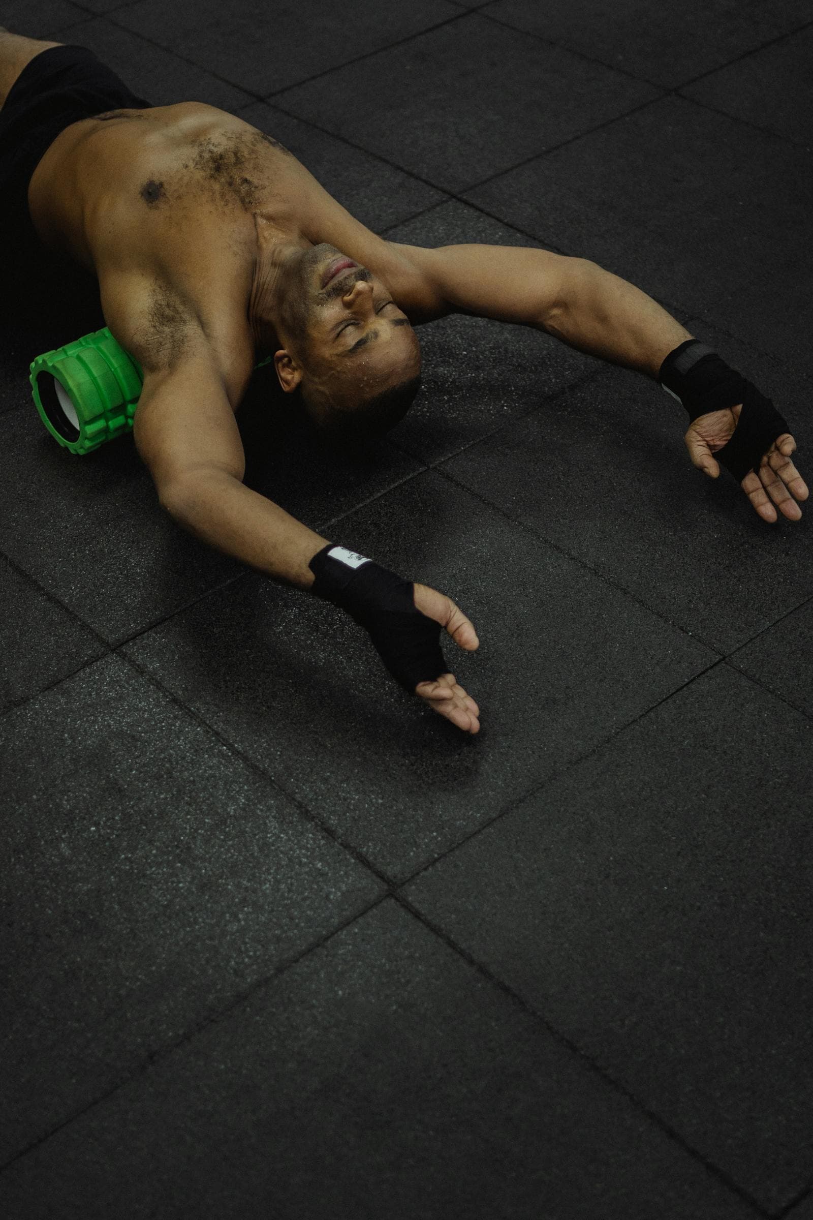 Yoga teacher releasing the upper back over a foam roller on the studio floor