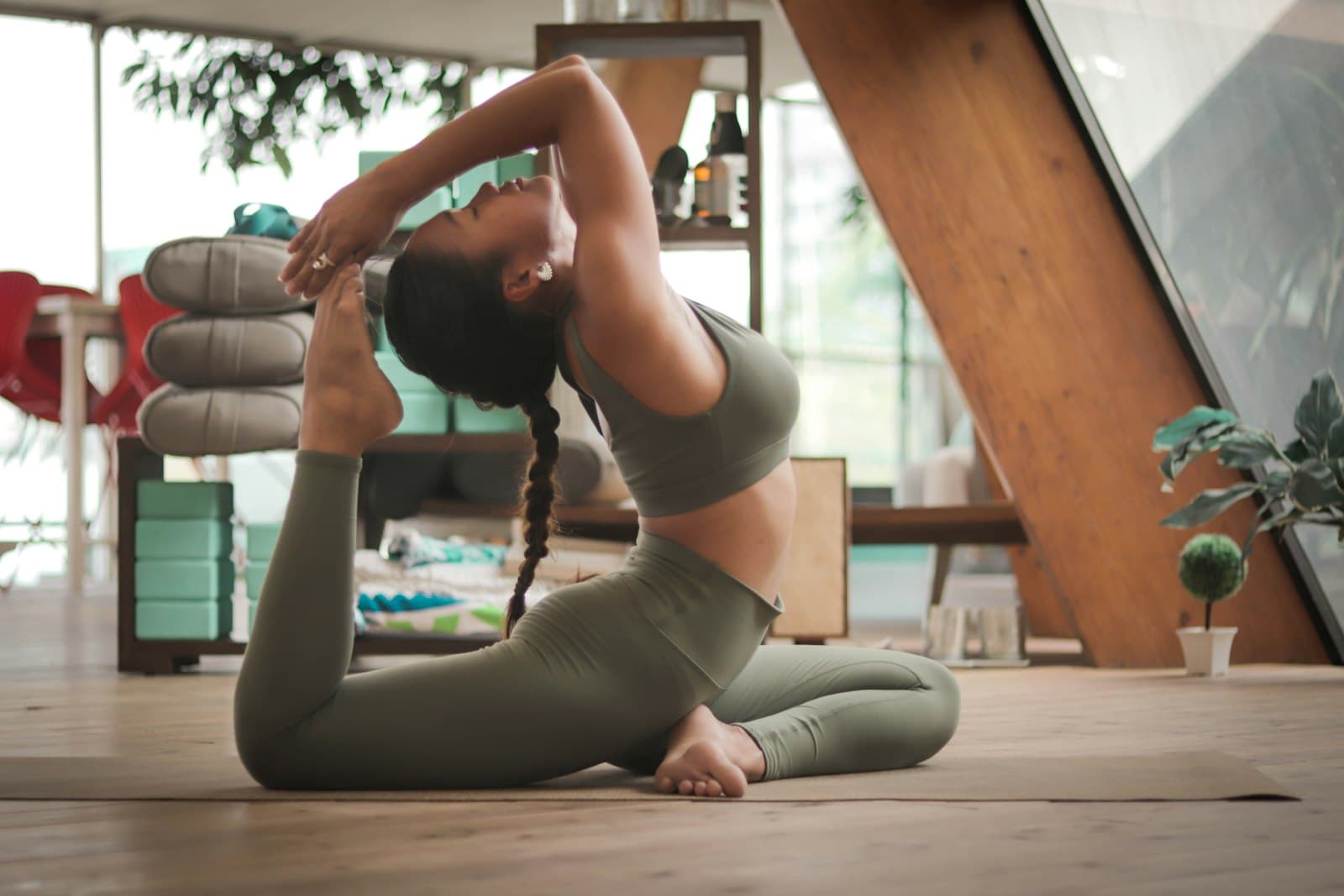 Practitioner in a supported supine yoga pose on a bolster with a single knee drawn toward the chest to ease sciatic nerve symptoms