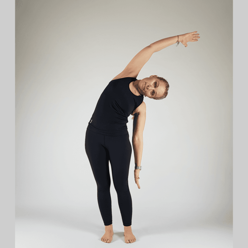 Standing Side Stretch bending to the left with arms overhead.