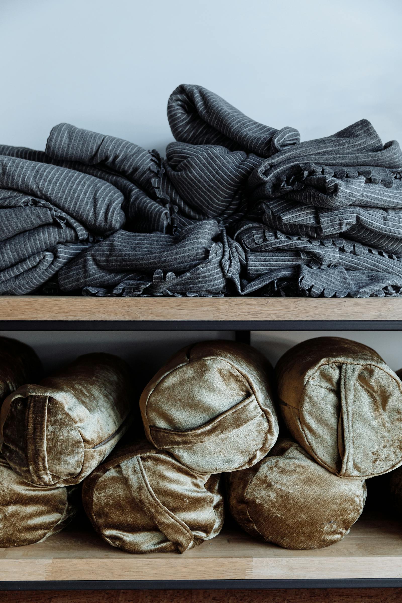 Stacked blankets and pillows on wooden studio shelves — the prop closet a yin teacher actually pulls from